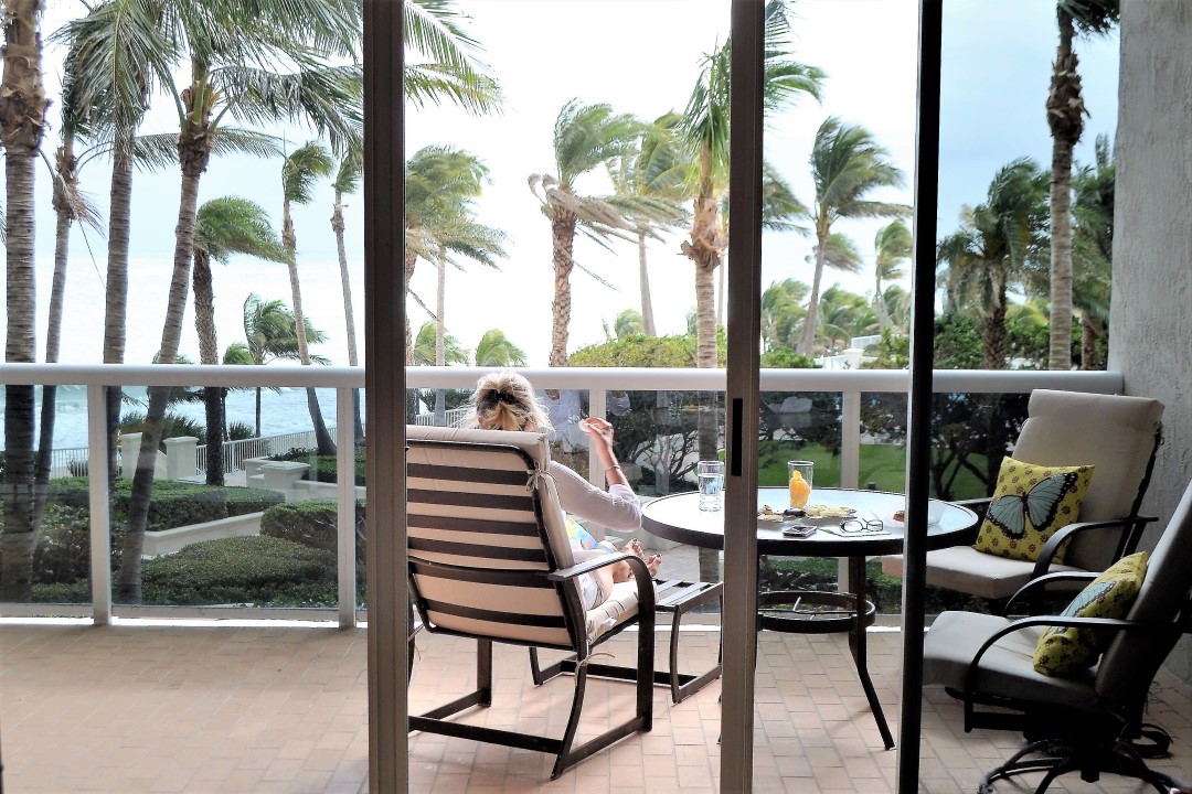 A senior woman relaxing on her lanai while watching her garden and drinking lemonade.